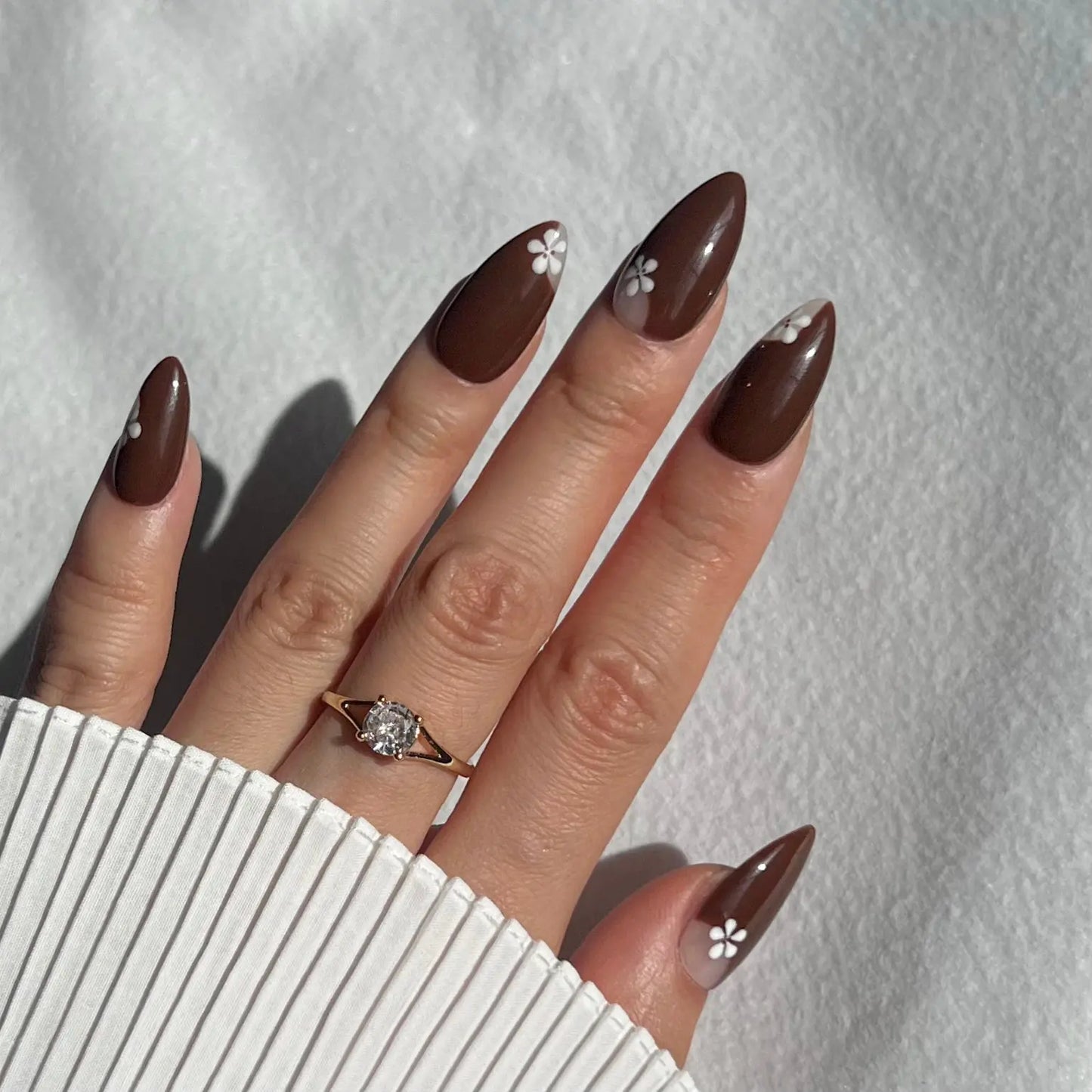 A hand showcasing sparkly press-on nails with a glossy finish, offering a sophisticated and glamorous appearance.