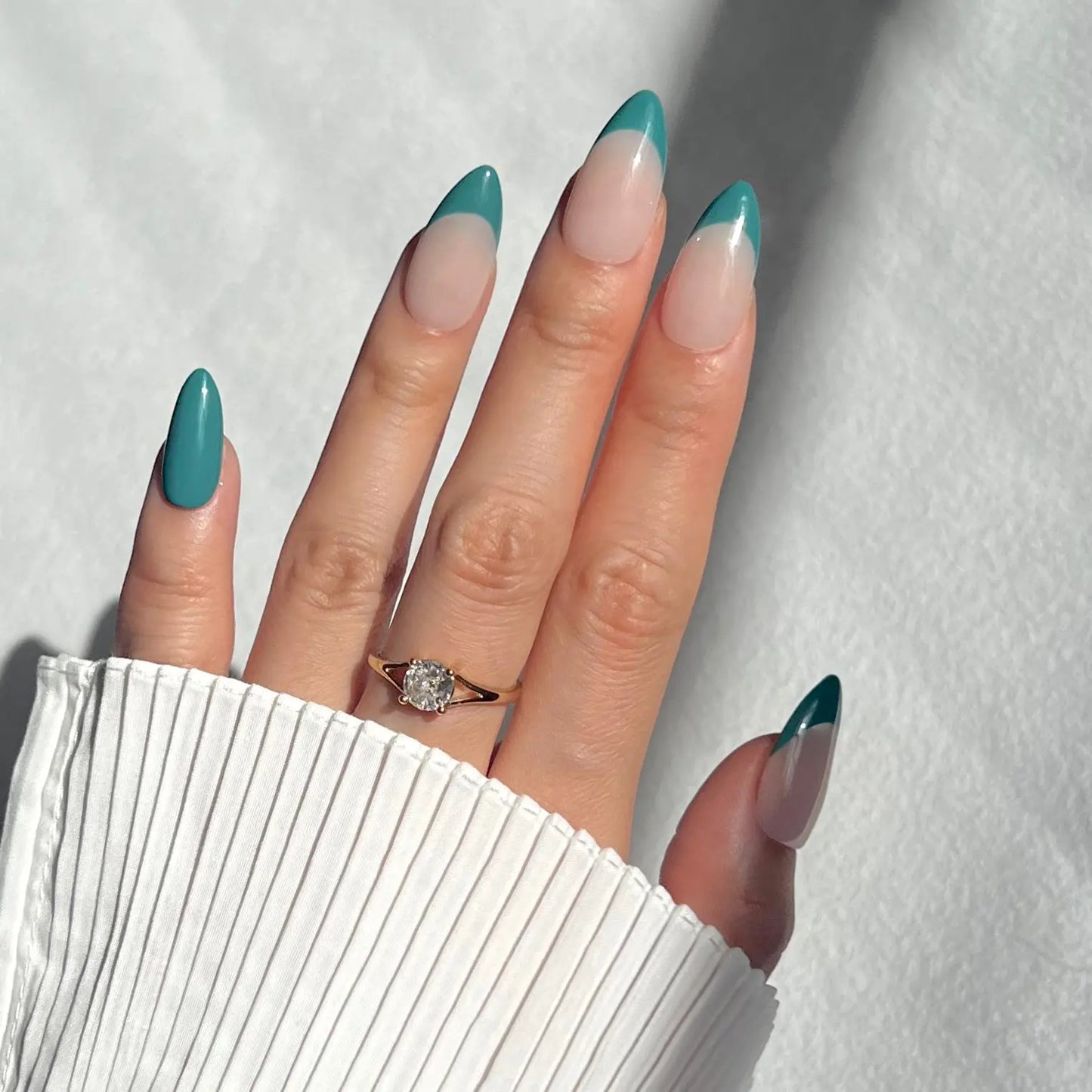 A hand showcasing press-on nails with striking jade green tips and a nude base, perfect for a refined, modern look.