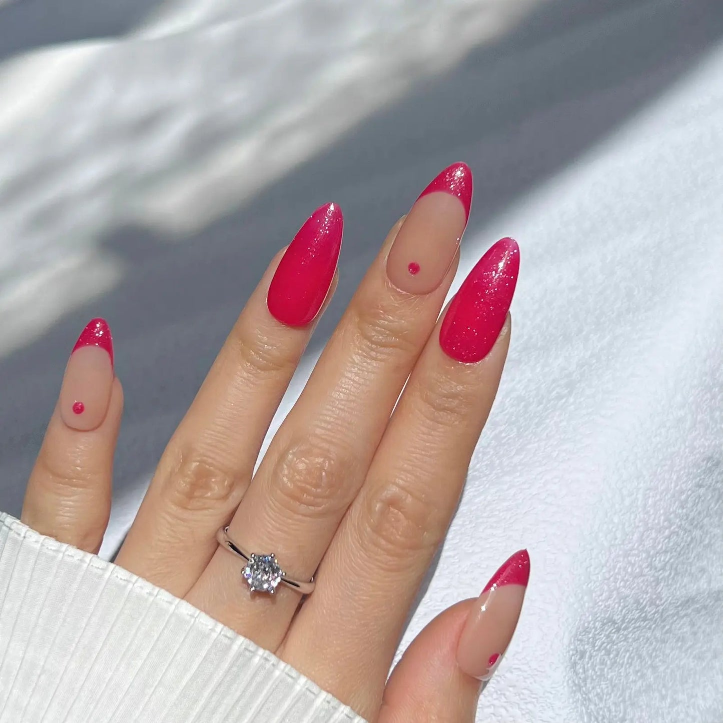 A hand showcasing magenta-colored press-on nails with a glittery finish, perfect for a bold, confident style statement.