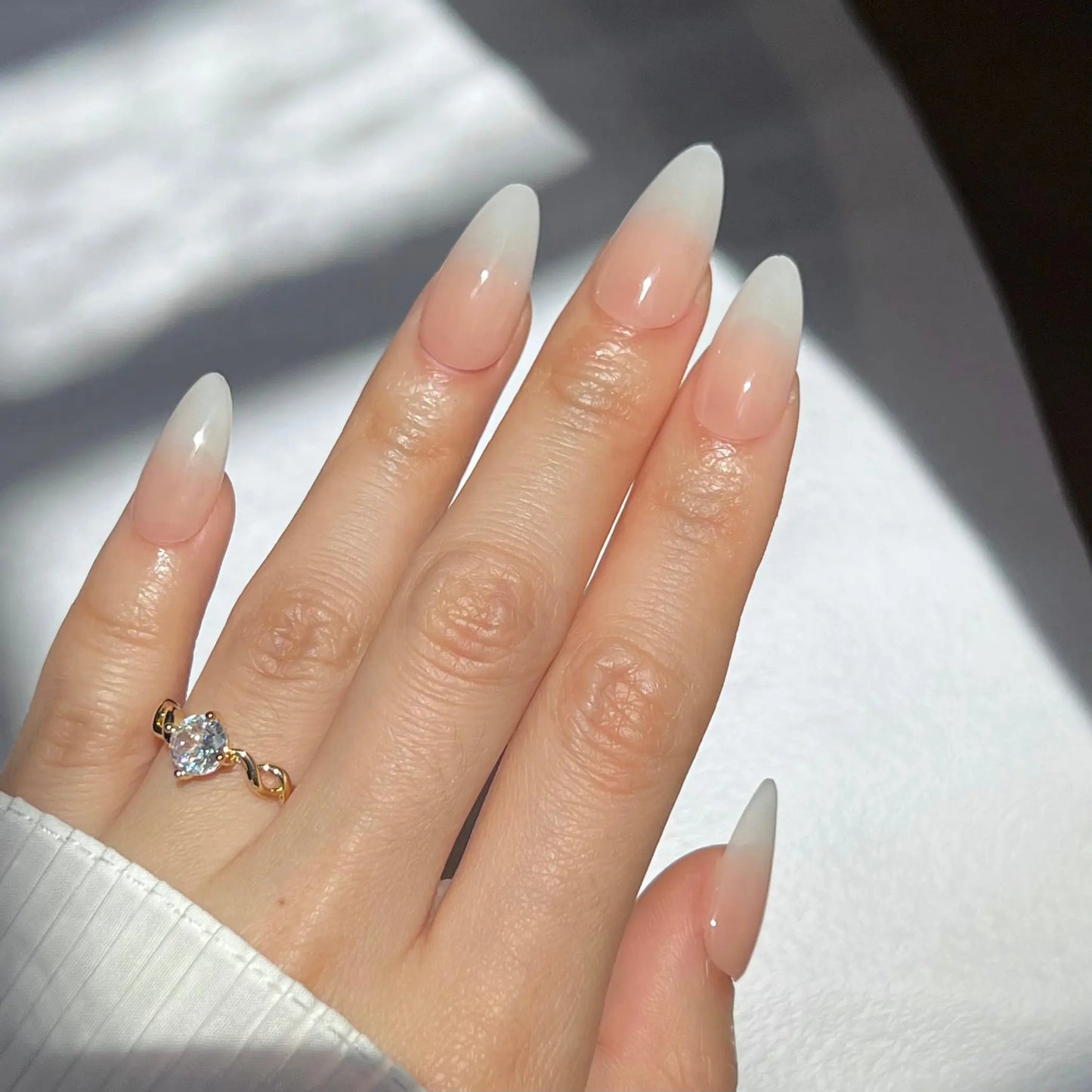 A hand showcasing peach-colored press-on nails with a shiny, smooth finish, giving off a polished and minimalistic style.